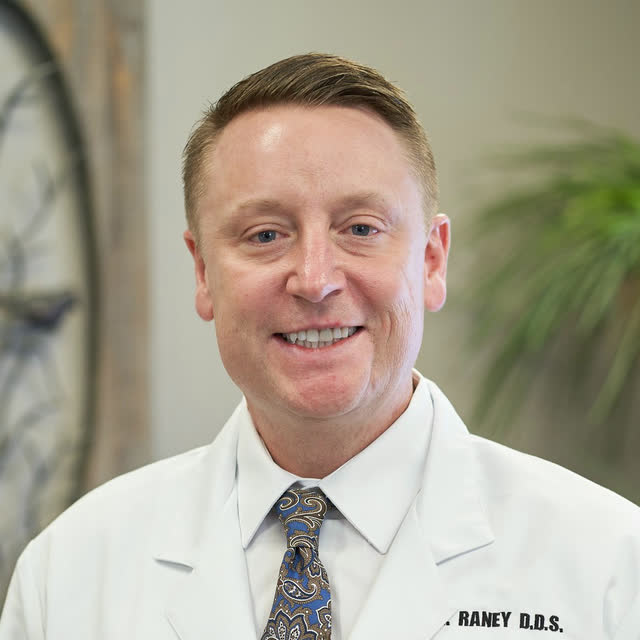 Dr. Rick Raney in a white coat with the Goose Creek Dental Clinic mark on the pocket.